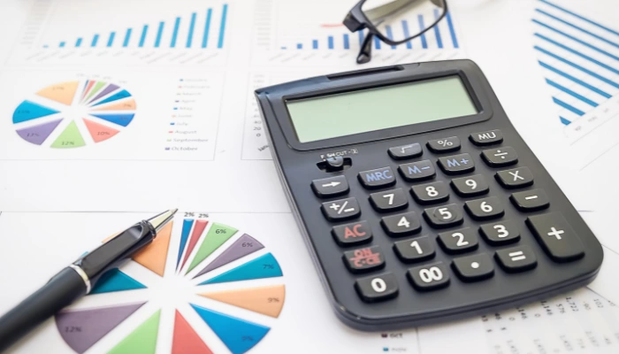 Investment papers and a calculator on a desk